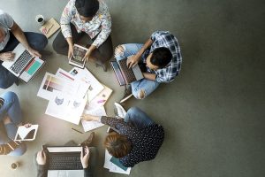 Imagem de pessoas sentadas em circulo trabalhando com notebook no colo